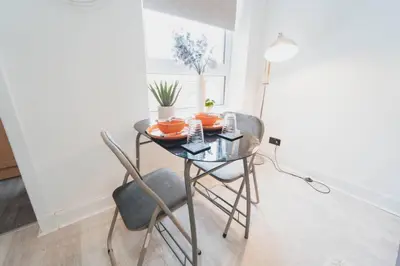 a dining room table with two chairs and a glass table at Top Floor 1BR Wishaw Flat with Parking in Wishaw