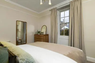 a bedroom with a bed and a mirror and a window at 3-Bed Georgian Townhouse Next to Wellbeing Clinic in Stirling