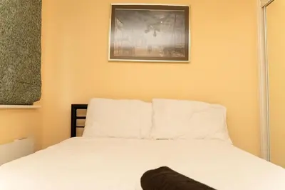 a bedroom with a white bed with a picture on the wall at 2 bed flat near Livingston North Station in Livingston