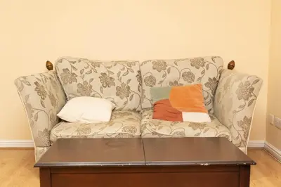 a couch with two pillows on it in a living room at 2 bed flat near Livingston North Station in Livingston