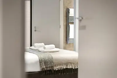 a bathroom with a mirror and towels on a bed at Stylish 2-Bedroom Flat On Seven Sisters Rd in Moffat