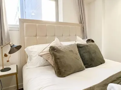 a white bed with pillows on it with a window at Stunning River View City Centre Apartment in Glasgow