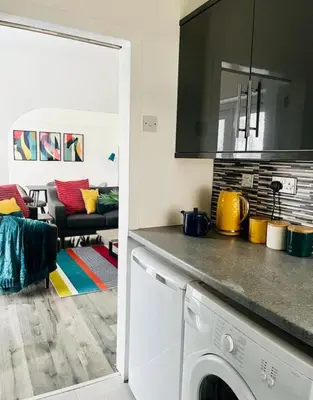 a kitchen with a washing machine and a living room at Clyde Fifty Two - Glasgow Apartment in Glasgow