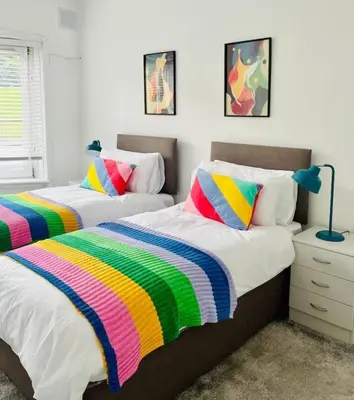 two beds with colorful blankets in a bedroom at Clyde Fifty Two - Glasgow Apartment in Glasgow