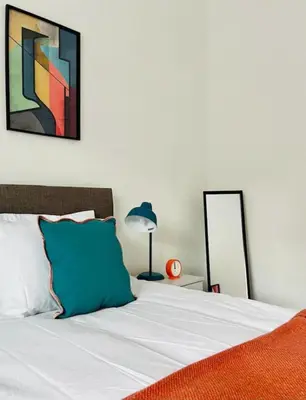 a bedroom with a bed with a blue pillow and a lamp at Clyde Fifty Two - Glasgow Apartment in Glasgow