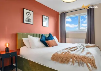 a bedroom with a bed with orange walls and a window at 3Bed House I Sleeps 6 I Dunfermline in Dunfermline