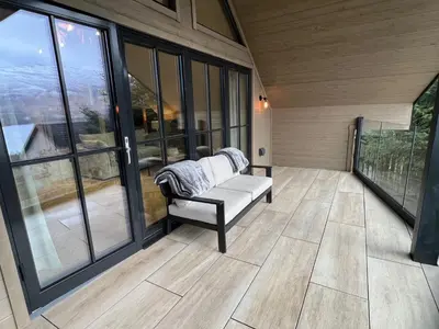 a screened in porch with a couch on a balcony at Highland House in Lochearnhead