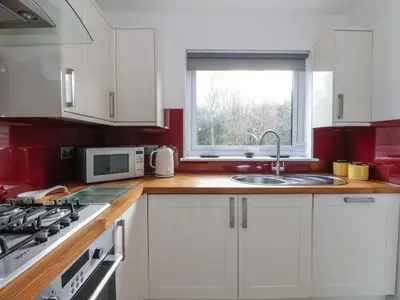a kitchen with white cabinets and a sink and a window at Sealladh in Appin