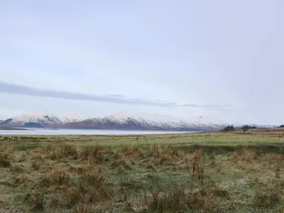 a field with snow covered mountains in the background at Sealladh in Appin