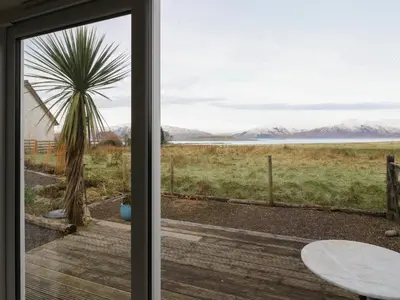 a sliding glass door leading to a patio with a palm tree at Sealladh in Appin