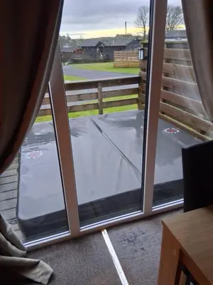a sliding glass door with a view of a driveway at Redwood lodge with luxury hot tub at Three lochs holiday park in Balminnoch