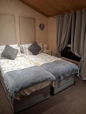 a bedroom with a bed and a window at Redwood lodge with luxury hot tub at Three lochs holiday park in Balminnoch