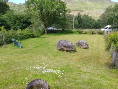 a park with rocks and a bench in the grass at Holiday Home Benmore Farm House in Stirling mit Bergblick by Interhome in Crianlarich