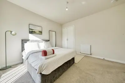 a bedroom with a large bed with white walls at Stylish and Morden 3Bed House Glasgow City Centre in Glasgow