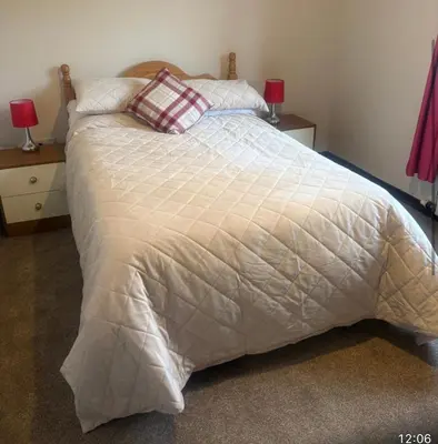 a bedroom with a bed with a white comforter at Lynndale in Carradale