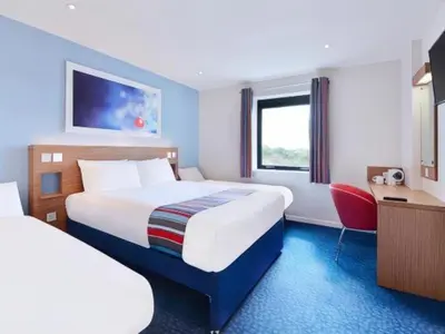 a hotel room with two beds and a desk at Travelodge Kinross M90 in Kinross