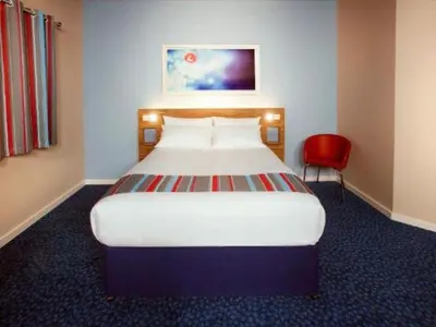 a bedroom with a large bed and a red chair at Travelodge Kinross M90 in Kinross