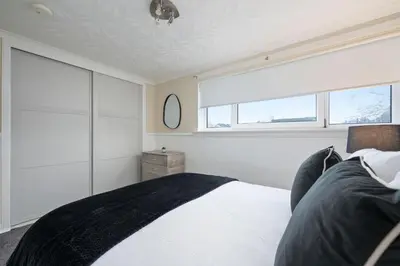 a bedroom with a large bed and a window at 2BR Sleeps 6 with Parking Near Linlithgow Palace in Linlithgow