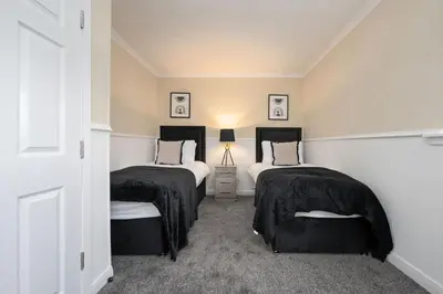 a bedroom with two beds with black covers at 2BR Sleeps 6 with Parking Near Linlithgow Palace in Linlithgow