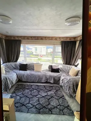 a living room with a couch in front of a window at Sandylands caravan park in Stevenston