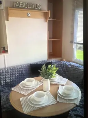 a table with plates and a vase of flowers on it at Sandylands caravan park in Stevenston