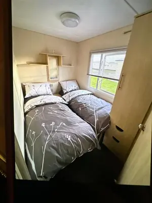 a bedroom with two beds and a window at Sandylands caravan park in Stevenston