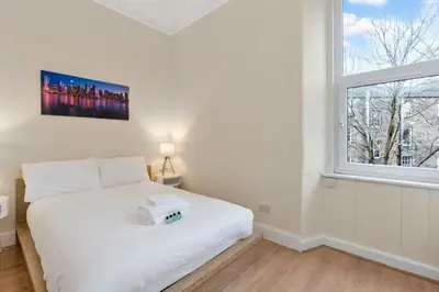 a bedroom with a white bed and a window at Charming City View Apartment with Modern Comforts in Edinburgh