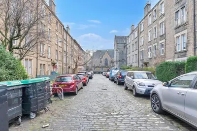 a row of cars parked on a street with buildings at Charming City View Apartment with Modern Comforts in Edinburgh