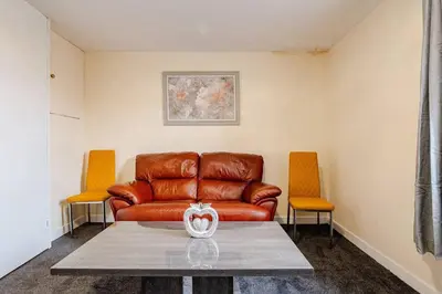 a living room with a leather couch and two chairs at Cosy Retreat - Suite 5 in Hamilton
