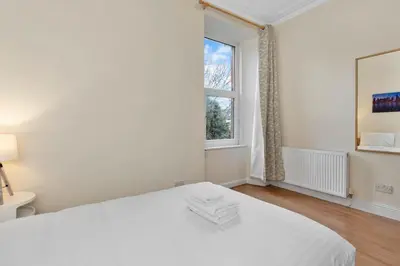 a white bedroom with a bed and a window at Great location Edinburgh city centre in Edinburgh