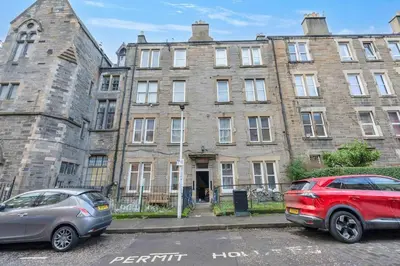 two cars parked in front of an old building at Great location Edinburgh city centre in Edinburgh