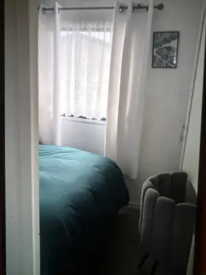 a bedroom with a bed and a window with a chair at Sandylands caravan park in Stevenston