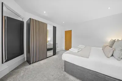 a white bedroom with a bed and a large mirror at The Nook - Beachwalk Apartments in Ayr