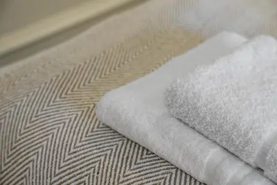 a stack of white towels on a bed at The Nook - Beachwalk Apartments in Ayr
