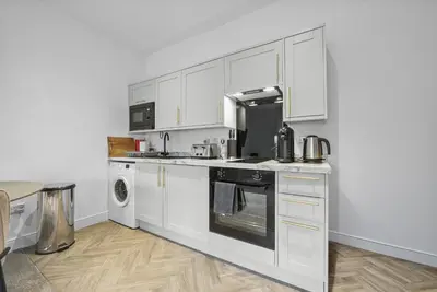 a kitchen with white cabinets and a dishwasher at The Nook - Beachwalk Apartments in Ayr