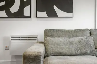 a couch in a living room with two pictures on the wall at The Nook - Beachwalk Apartments in Ayr