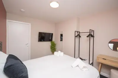a bedroom with two beds and a tv on the wall at Vacant Nests Unique 4BR home The Muirhouse in Motherwell