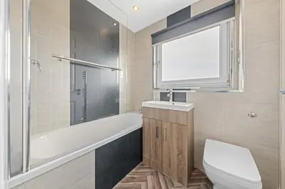 a bathroom with a toilet and a tub and a sink at The Brora in High Blantyre