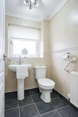 a bathroom with a toilet and a sink and a window at Jake's House in Airdrie
