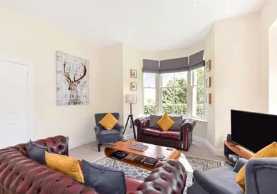 a living room with leather furniture and a tv at Balmore - 3 Bedroom Townhouse, heart of Killin in Killin