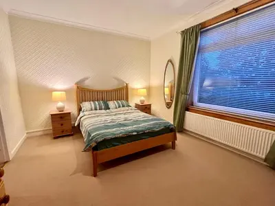 a bedroom with a bed and a large window at Cosy 2-Bed Villa in Knightswood