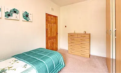 a bedroom with a bed and a wooden dresser at Cosy 2-Bed Villa in Knightswood