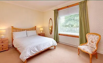 a bedroom with a bed and a chair and a window at Cosy 2-Bed Villa in Knightswood