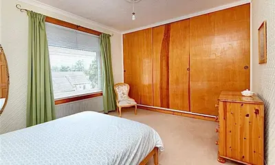 a bedroom with a bed and a chair and a window at Cosy 2-Bed Villa in Knightswood