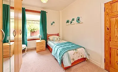 a bedroom with a bed and a dresser and a window at Cosy 2-Bed Villa in Knightswood