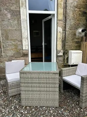 two wicker chairs and a glass table on a patio at 77 West Princes St, cosy 1 bed ground floor in Helensburgh