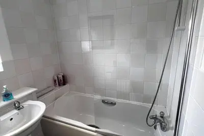 a white bathroom with a tub and a toilet at 2 Bed Apartment Sleeps 4 -Near Airport -WiFi & Tv in Renfrew