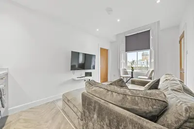 a living room with a couch and a tv at The Snug - Beachwalk Apartments in Ayr