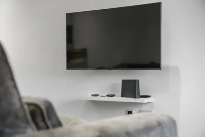 a living room with a tv and two chairs at The Snug - Beachwalk Apartments in Ayr