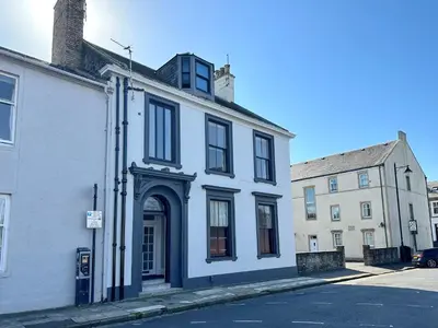 a white building with a blue door on a street at The Snug - Beachwalk Apartments in Ayr